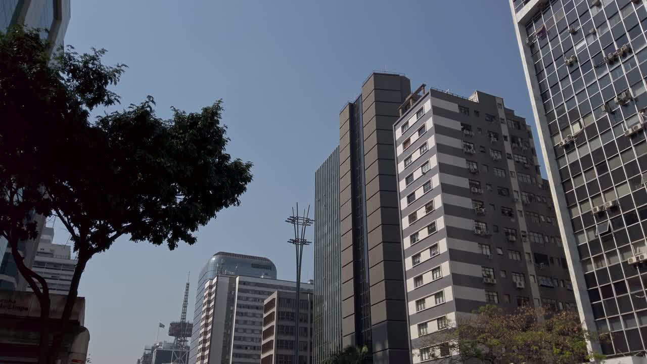 Buildings and traffic on Avenida Paulista on sunny day, Brazil. Tilt up