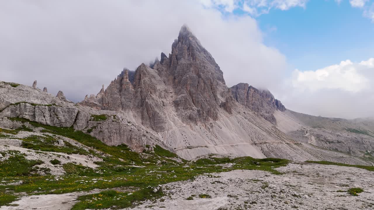 Epic aerial orbit of Dolomite Alps, panning left with clouds over peaks near sunset in 4K