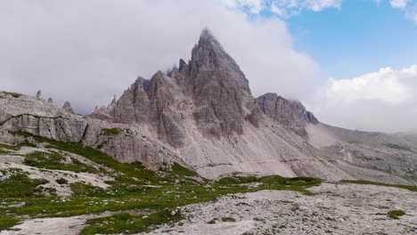 epic aerial orbit of dolomite alps, panning left with clouds over peaks near sunset in 4k