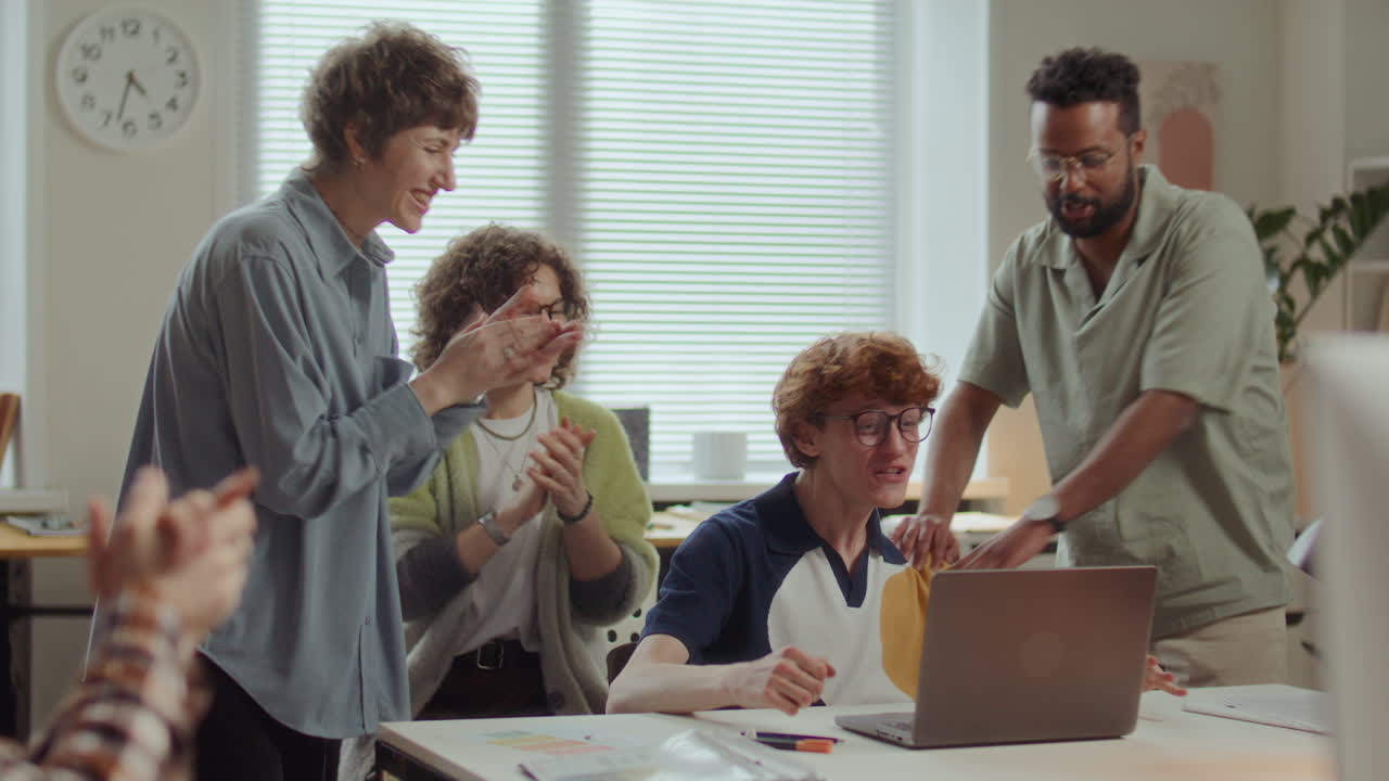 Young Man Celebrating Success with Diverse Business Team in Office