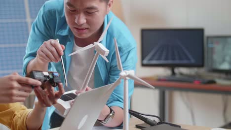 close up of asian man and woman discuss about work with circuit board, wind turbine and laptop computer