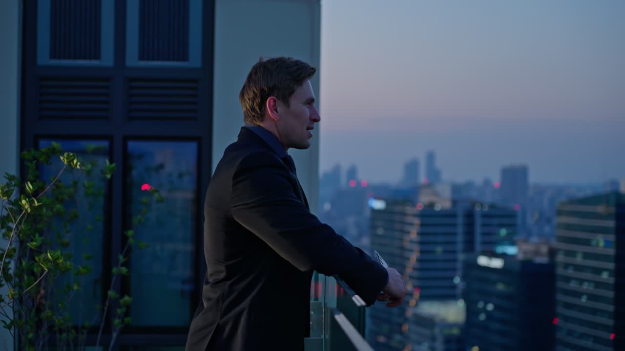 A businessman celebrates with a smile and clenched fist after receiving great news on his phone, standing on a rooftop with a view of Seoul's evening skyline