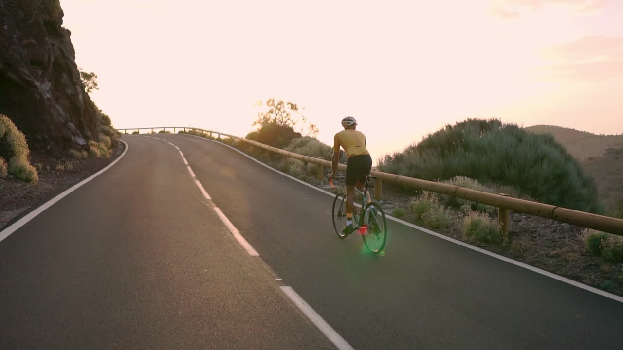 In slow motion, athlete on a bicycle traverses a mountain serpentine, basking in the island's beauty, a true embodiment of a healthy lifestyle