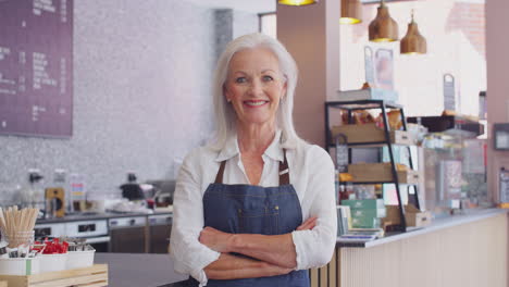 Portrait-Of-Mature-Female-Owner-Of-Coffee-Shop-Or-Restaurant-Using-Digital-Tablet