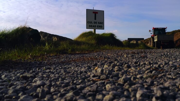 Establishing shot of a tractor driving through a rural area, passing a cul-de-sac sign