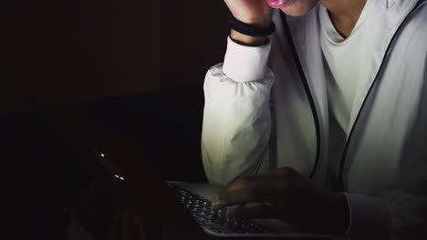 Close-up of serious young man using laptop at night