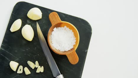 slice garlics with salt and knife on chopping board 4k