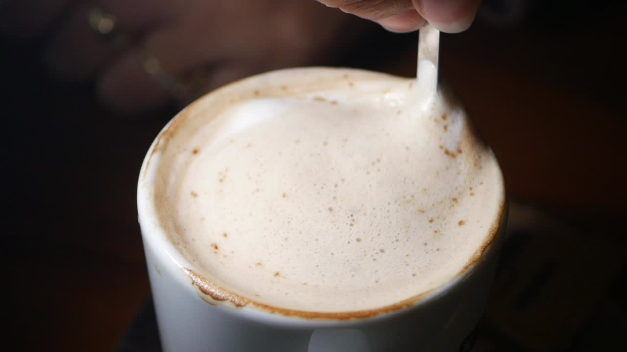 Someone stirring a coffee drink