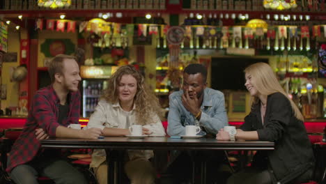 Happy-group-of-friends-chatting-and-having-drinks-in-city-coffee-shop