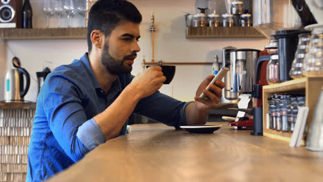 male business executive using mobile phone while having coffee