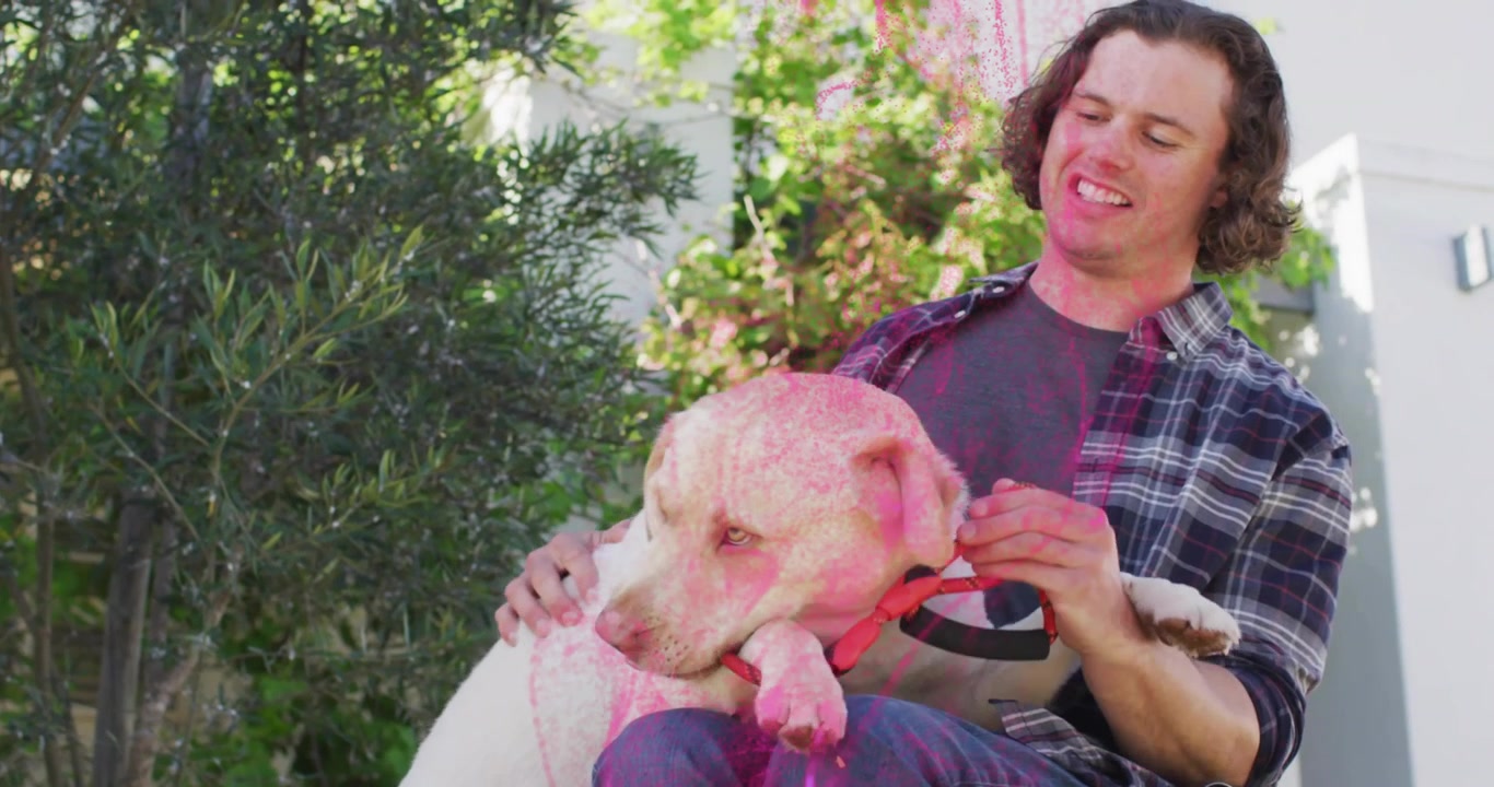 Jovem Brincando com Seu Cachorro Coberto com Pó Holi Rosa
