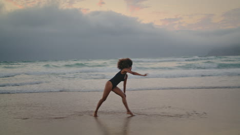 girl making wheel beach sand gloomy evening. woman performing acrobatic element.