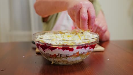 homemade latvian salad layering with chopped egg, grandmother in kitchen light