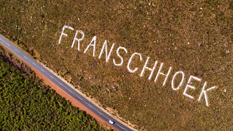 coche que conduce el paso de montaña y el nombre de franschhoek en la ladera de la montaña