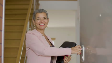 vista frontal de un agente inmobiliario sonriente abriendo la puerta de la casa