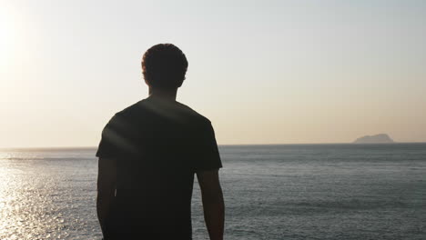 silhouette man walking on sea cliff at sunset