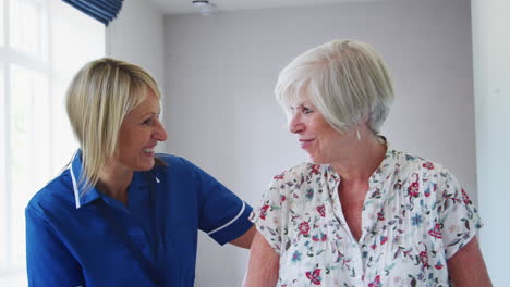 nurse helping senior woman walk using a walking frame