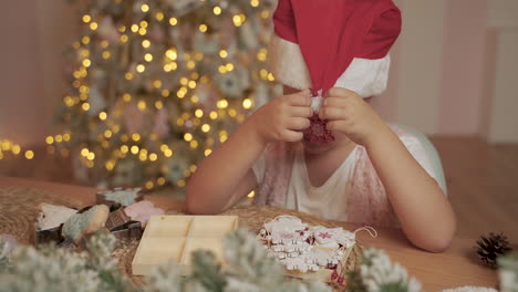 little girl decorates her santa hat with christmas decorations