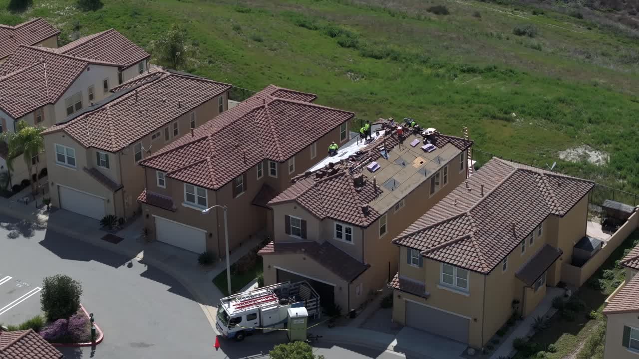 Solar panels being installed on top of residential home in suburban area, aerial descending view