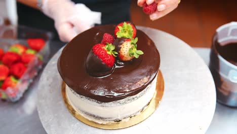 baker adding fresh fruit to chocolate cake for decoration