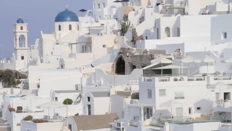 view of a traditional cycladic architecture village with a blue domed greek orthodox chapel visible