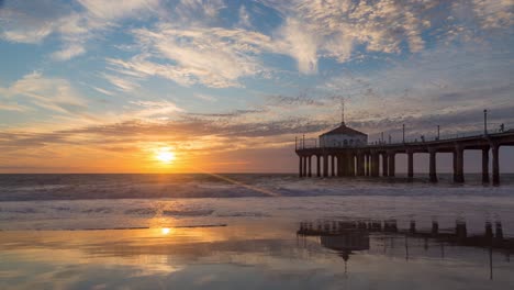 olas tranquilas y reflexión en el muelle de manhattan beach durante la puesta de sol en california, ee.uu.