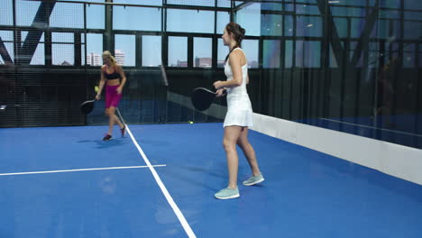 women playing padel tennis on indoor court, focusing on competitive match