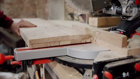 cámara lenta de cerca, el maestro corta una tabla de madera con una sierra circular en el taller de carpintería de un pequeño fabricante de muebles. v3