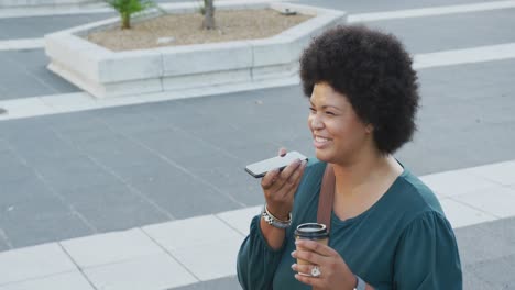 Happy-plus-size-biracial-woman-talking-on-smartphone-and-drinking-coffee