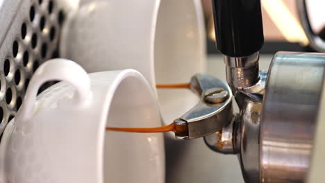 4k-Vertikaler,-Kräftiger-Brauner-Kaffee-Gießt-Aus-Der-Espressomaschine-In-Zwei-Weiße-Tassen