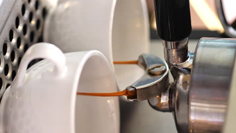 4k vertical, rich brown coffee pours from espresso machine into two white mugs