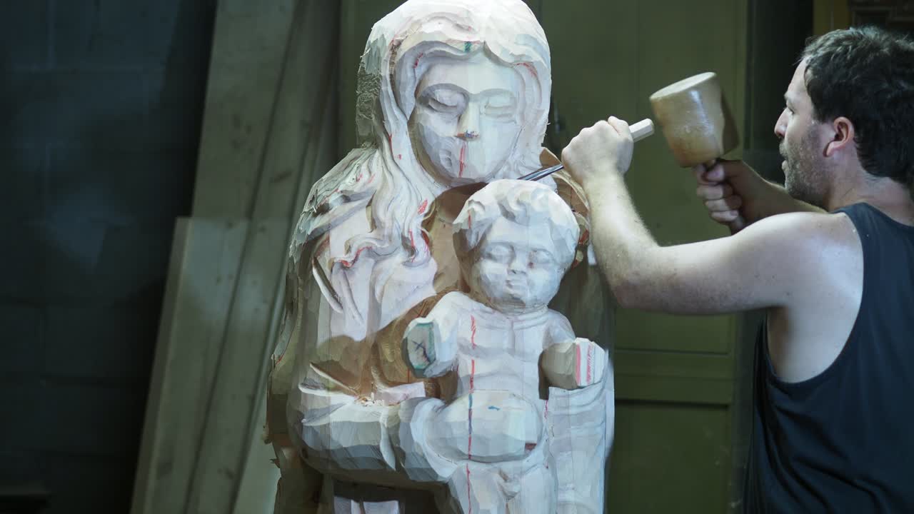 Skilled artisan meticulously carves a wooden sculpture of the Madonna and Child in his workshop using traditional tools and techniques with precision and dedication to the craft