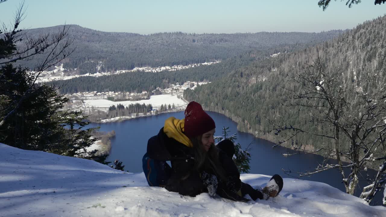 한 젊은 여성이 보스게스 산맥에 있는 롱게머 호수 위의 전망대에 도달한 후 휴식을 취하기 위해 눈 위에 누워 있습니다.