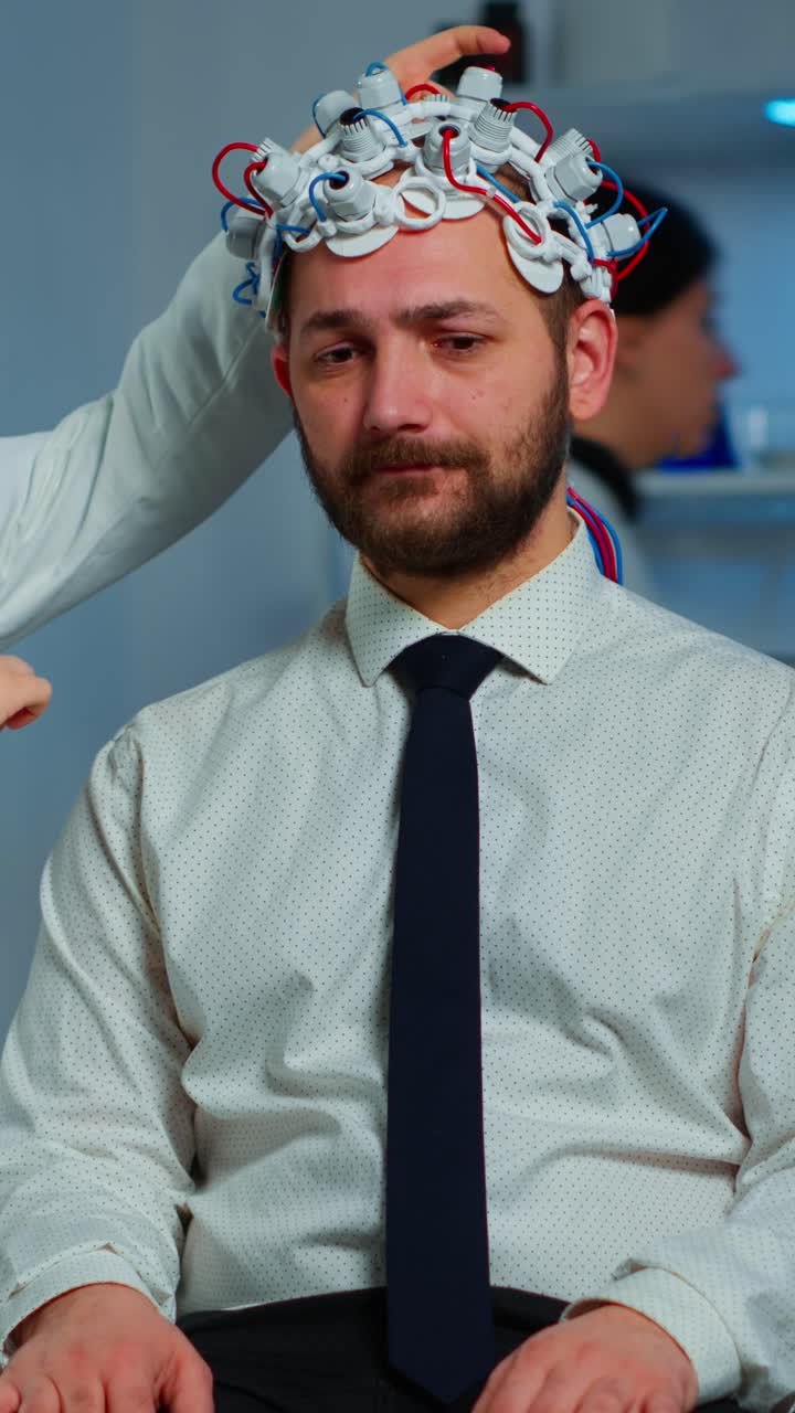 Man undergoing an EEG brain activity test with electrodes applied by a medical professional