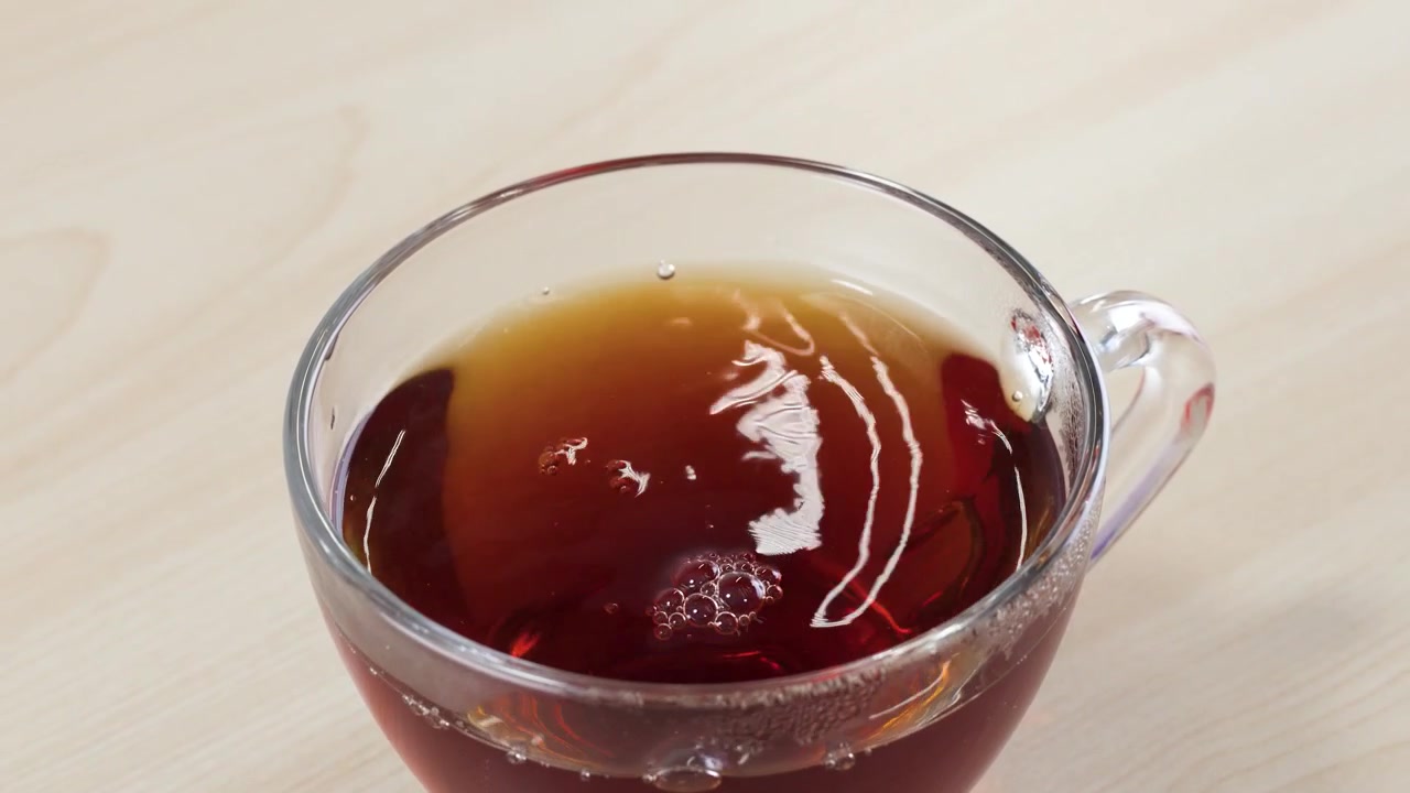 テーブルの上で透明なガラスカップに注がれ、琥珀色の紅茶が抽出される様子