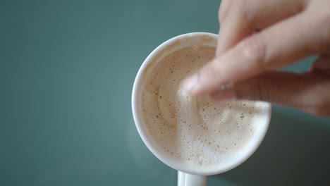 la mano mezclando una bebida de café