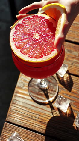 refreshing grapefruit cocktail preparation on a sunny wooden table