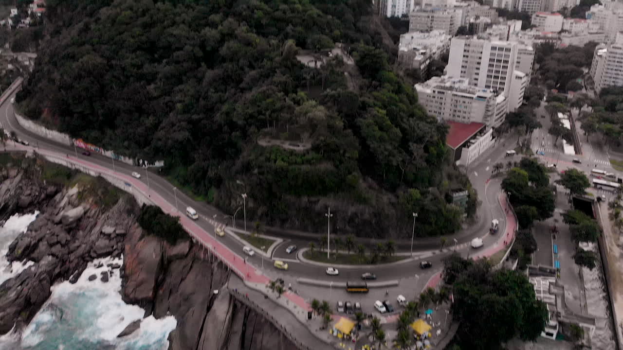 incline la vista aérea en el mirador de leblon y estacione con olas rompiendo en la costa rocosa que revela un día gris nublado en río de janeiro