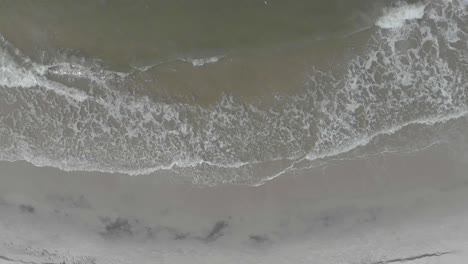 vacation concept top down aerial view on gentle waves on empty beach