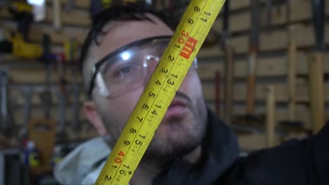 the man stands in the middle of the room, surrounded by various tools and materials scattered across the workbench