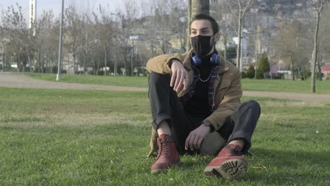 Young-Man-In-Mask-Sitting-At-Park