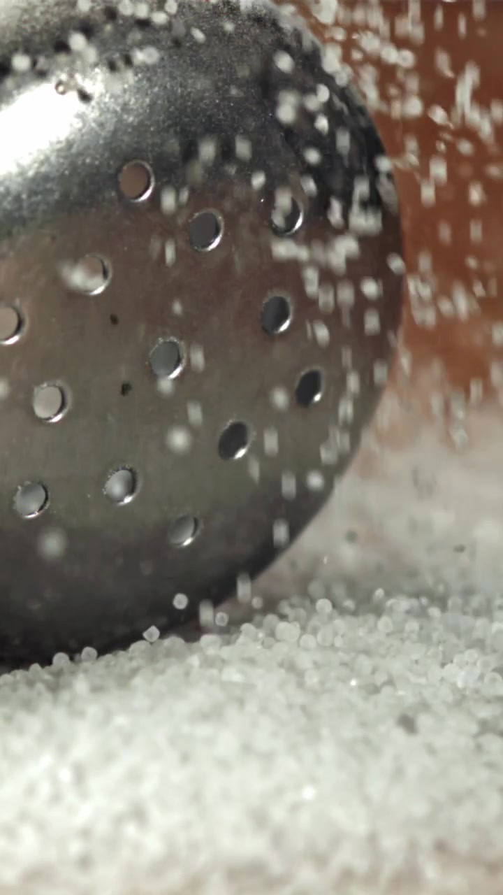 Slow Motion Close-up of Sugar Granules Falling on Metal Surface