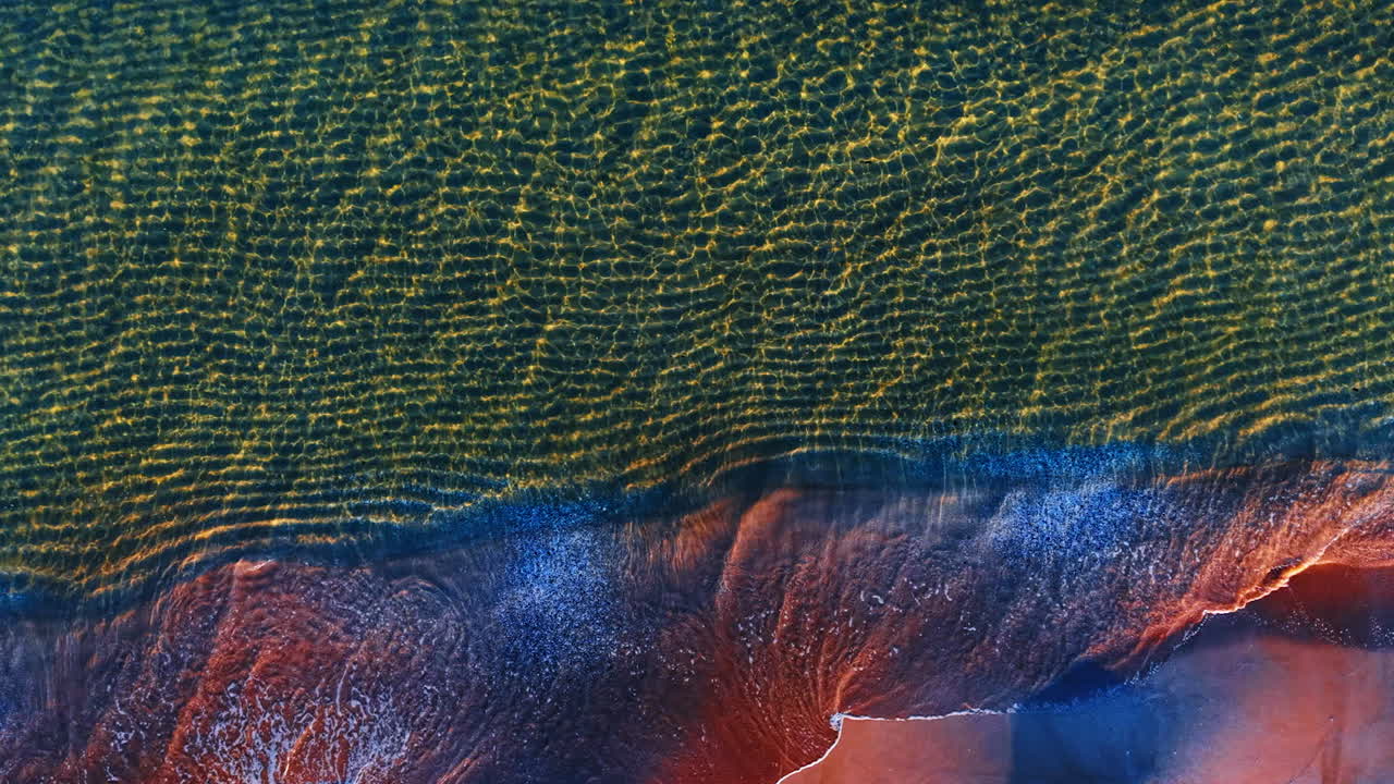 Ridged waterscape rolling waves to the shore. Drone flight over the coast of the sea with sandy beach