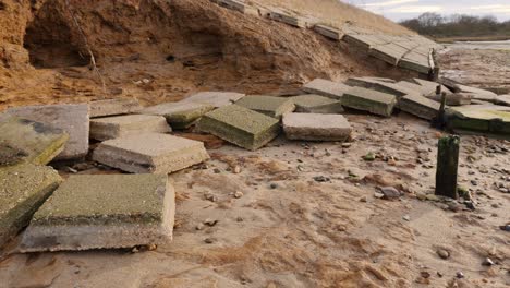 broken tiles scattered across beach from damaged sea wall