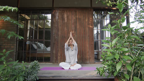 Focused-biracial-woman-practicing-yoga-on-terrace,-slow-motion