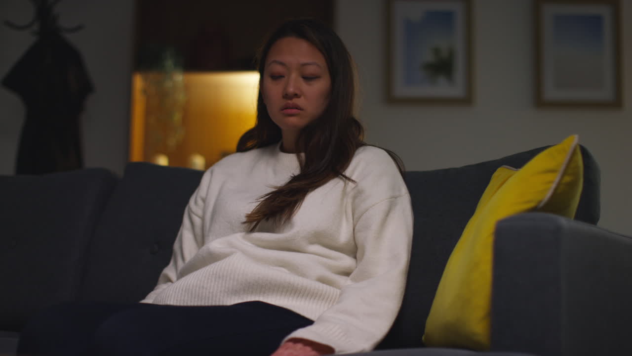 mujer estresada o ansiosa que sufre de depresión, ansiedad o soledad sentada en el sofá en casa por la noche 1
