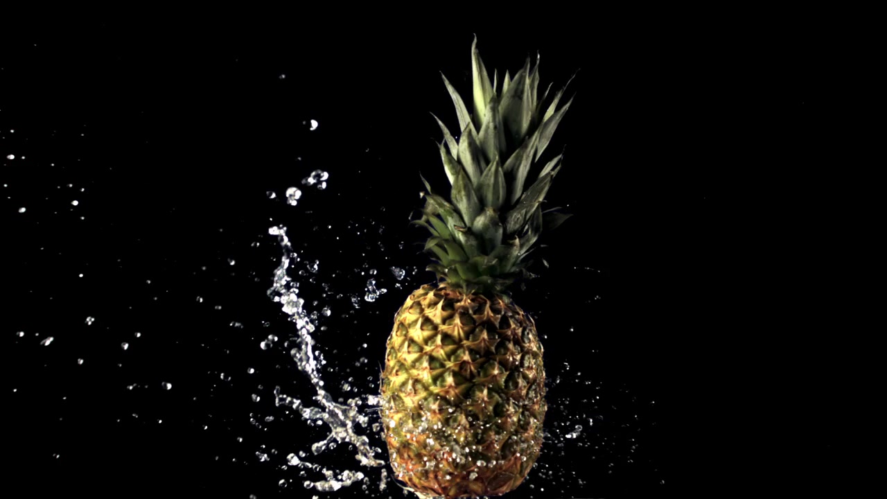 Fresh Pineapple Splashing with Water on Black Background in Slow Motion
