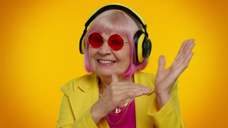 a happy senior woman in yellow jacket and pink hair listening to music