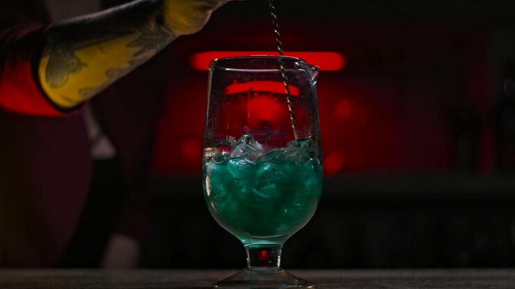 Barman che prepara un cocktail verde in un bar