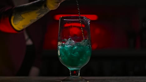 bartender preparing a green cocktail at a bar